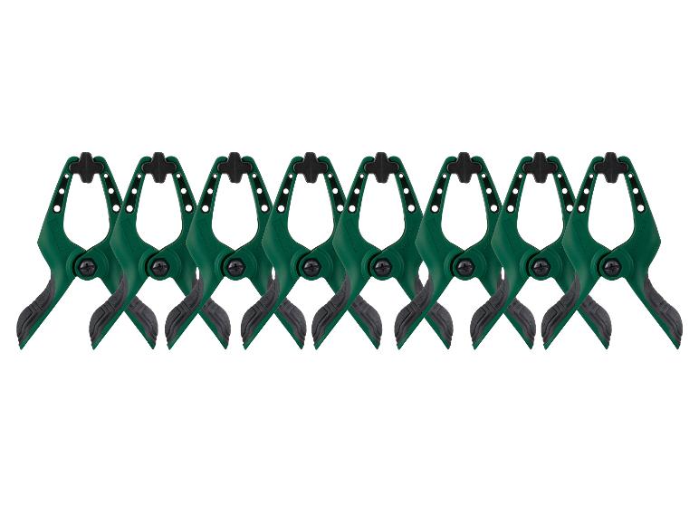 Acht groen-zwarte veerklemmen met rubberen handvatten, op een rij gerangschikt.