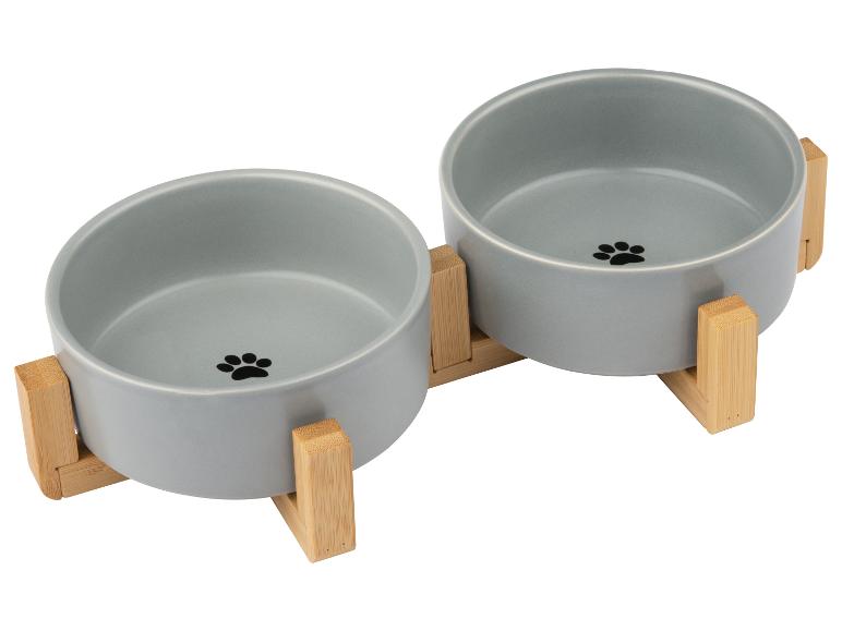 Twee grijze voerbakken voor huisdieren met pootafdrukken, op een bamboe standaard.
