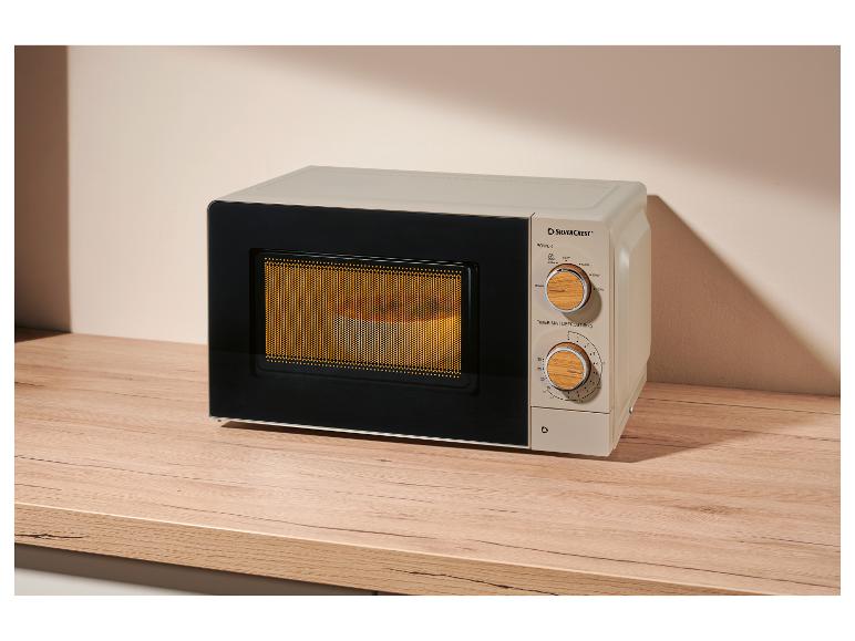 Beige magnetron met houten bedieningspaneel, op een houten tafel.