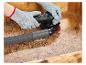 Handschoenen en schuurmachine schuren een houten oppervlak, met stofzuigerslang bevestigd.