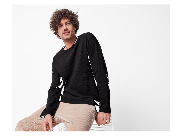 Mannelijk model in een zwarte trui en beige corduroy broek.