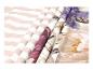 Gevouwen stoffen met strepen, bloemen en bladeren in paarse, beige en roze tinten.