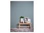 Lichtblauwe muur met een houten bankje, vazen, een houten hand en ingelijste foto's, één met 'dream'.