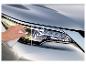 Hand polijst doffe autokoplamp, waarvan de rechterkant al glanzend is.