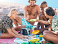 Vrienden genieten van een picknick met snacks en drinken op het strand.