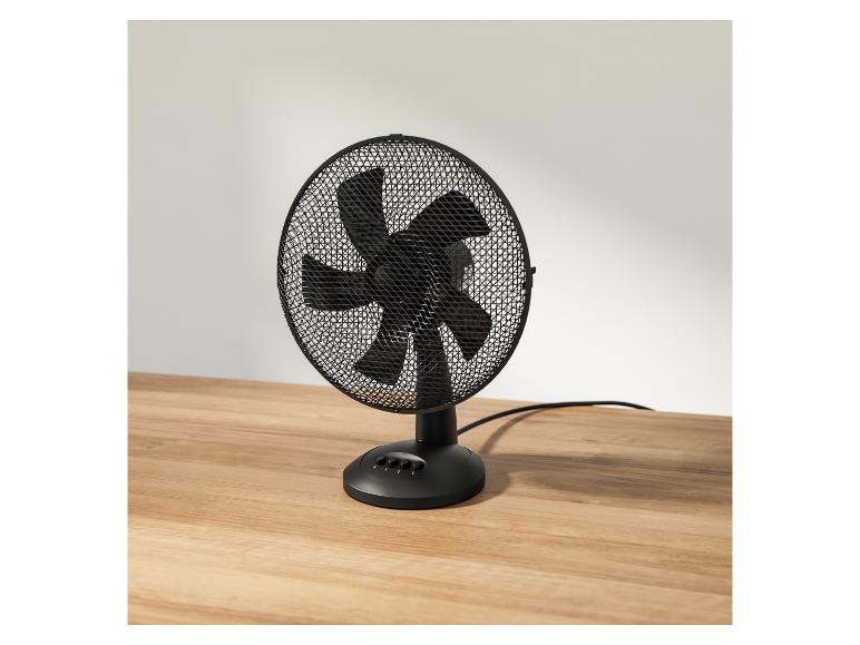 Zwarte tafelventilator op een houten tafel.