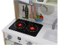 Houten speelkeuken met kookplaat, gootsteen, klok en decoratieve flessen en fruit.