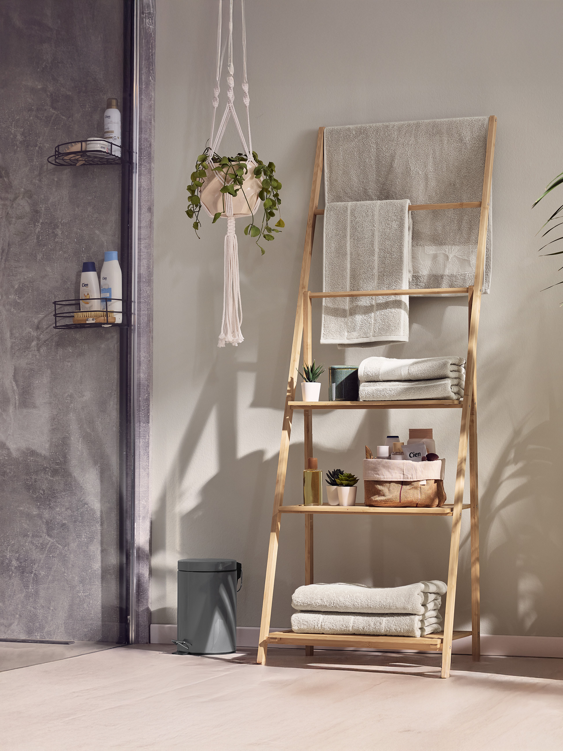 Bamboe ladderrek met handdoeken en badproducten in een moderne badkamer.