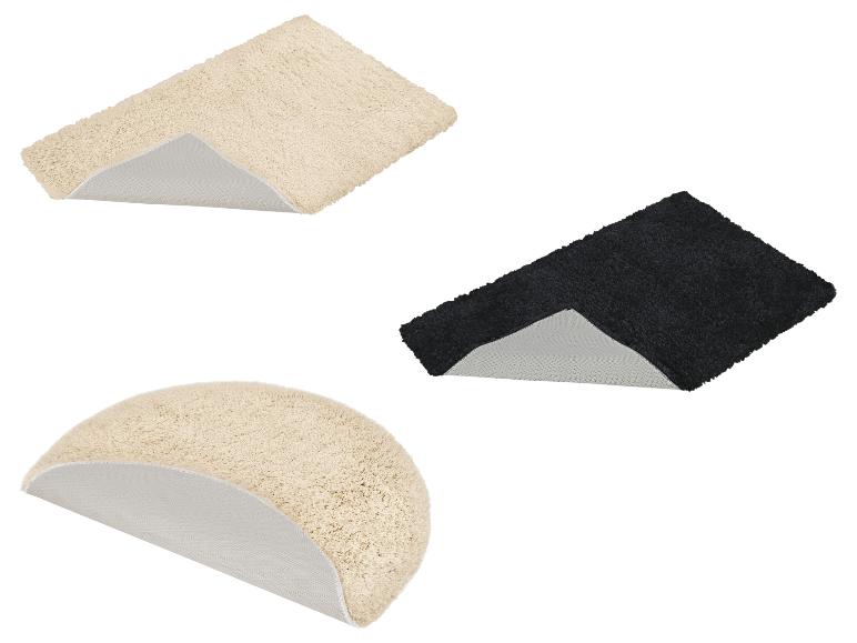 Twee rechthoekige badmatten in beige en zwart, en één beige halfronde badmat.
