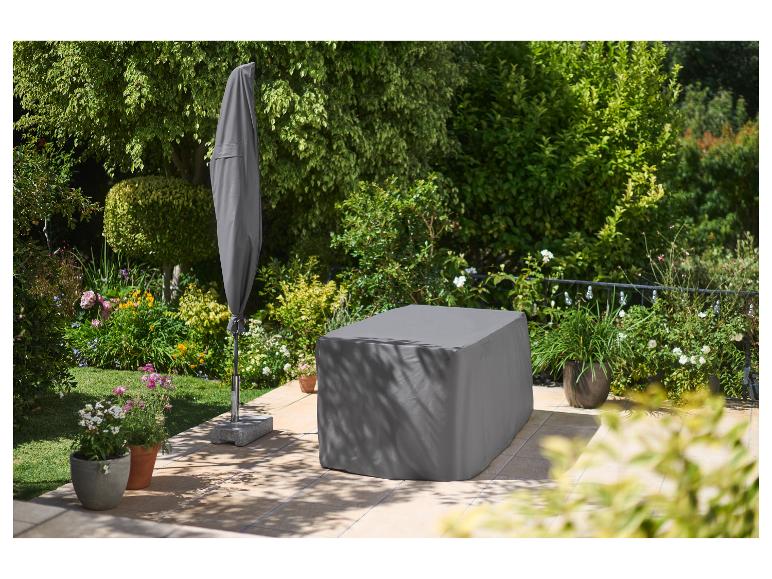 Tuinmeubelset en parasol bedekt met grijze beschermhoezen op een terras.