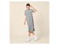 Vrouw in grijze T-shirtjurk, bril en witte sneakers, lachend.