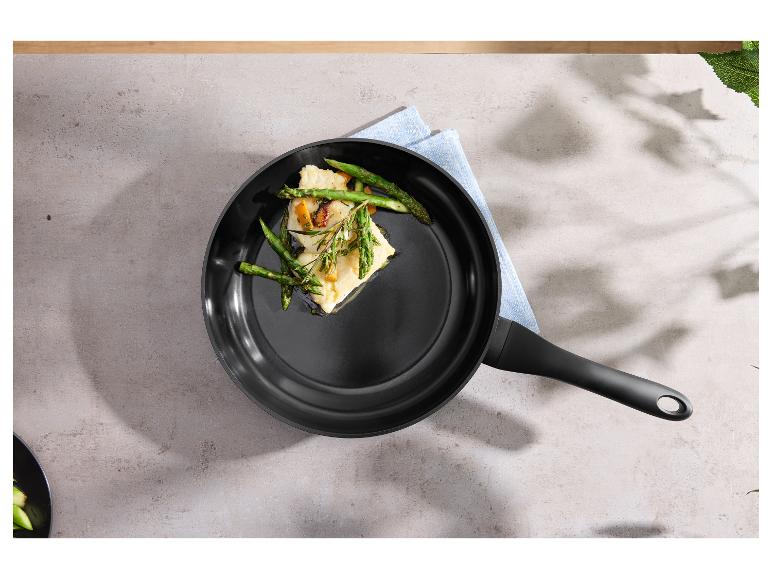 Koekenpan met vis en asperges op een grijs aanrecht met een blauwe doek