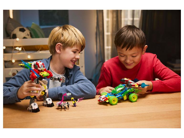 Twee jongens spelen met LEGO-sets, een robot en een raceauto, aan een houten tafel.