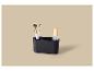 Zwarte make-up organizer met twee kwasten en een flesje op een beige achtergrond.