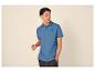 Man in blauwe poloshirt met palmboomlogo en donkere spijkerbroek.