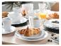 Ontbijttafel met croissants, koffie, sap en servies.