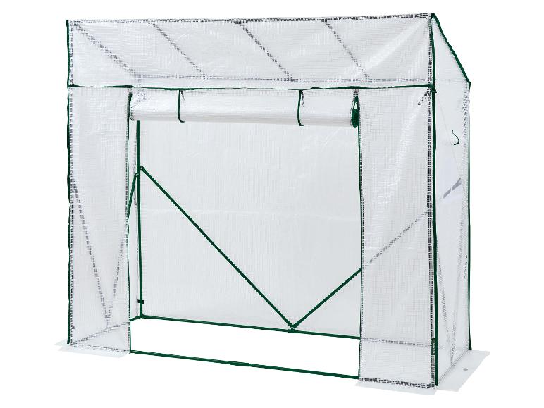 Een witte inloopkas met oprolbare deur en groen frame.