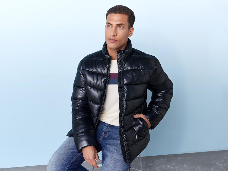 Een man draagt een zwarte winterjas en blauwe jeans.