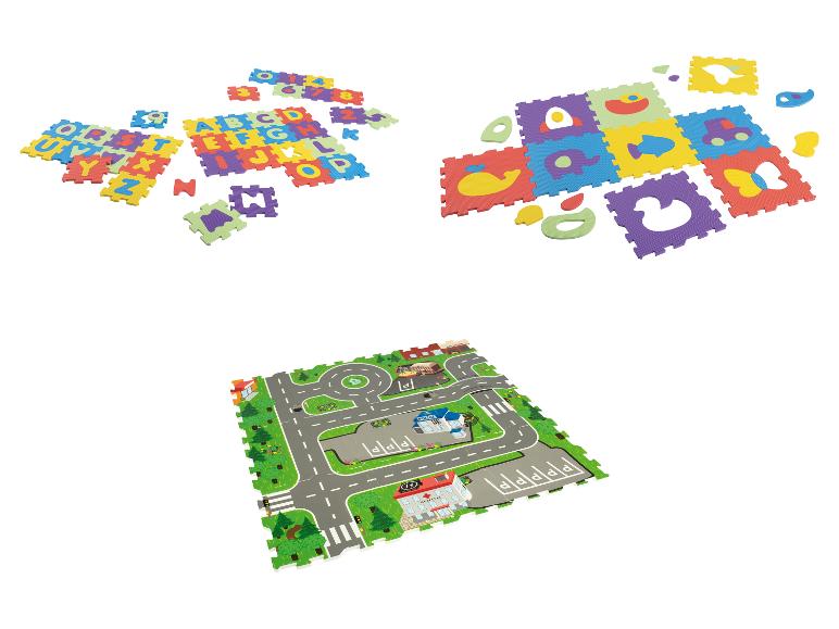 Een speelmat met letters, cijfers, dieren en een stad met wegen.
