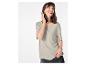 Lachende vrouw in lichtgrijs T-shirt en donkere jeans, hand in zak.