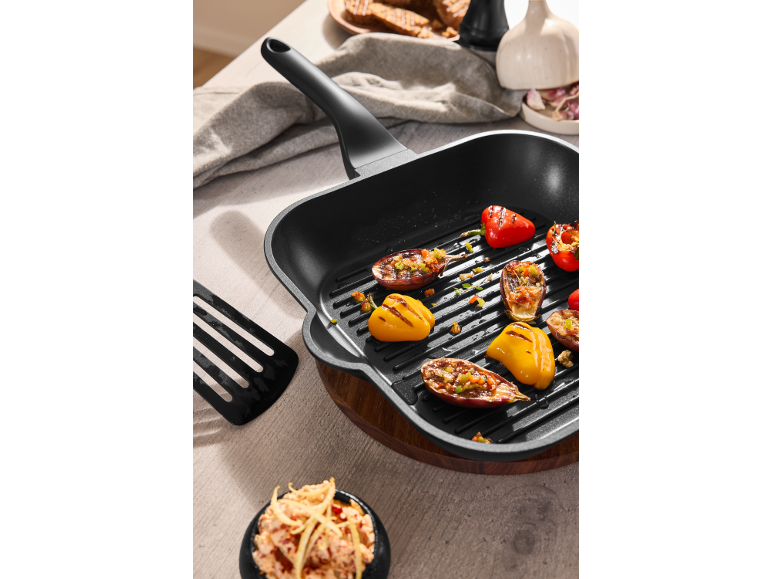 Zwarte grillpan met gegrilde groenten, waaronder paprika's en aubergines.