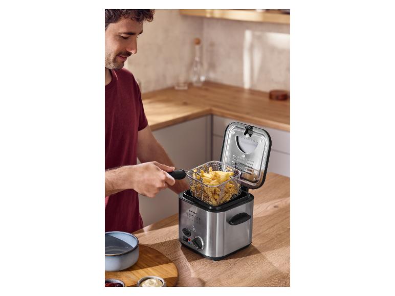 Man haalt de mand met frietjes uit de SILVERCREST® mini-friteuse.