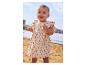 Baby in een beige bloemenjurk op het strand