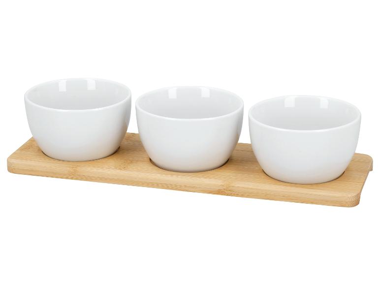 Drie witte keramische kommen op een bamboe dienblad.