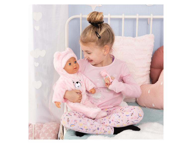 Meisje in pyjama houdt een pop in een roze berenpak vast.