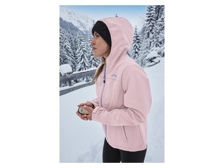Vrouw in roze CRIVIT thermo-softshelljas en muts in besneeuwd berglandschap.