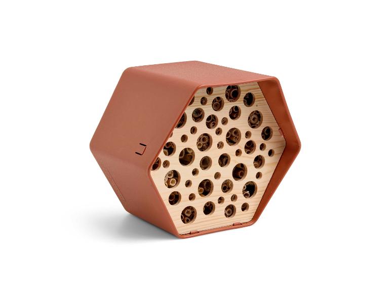 Zeshoekig insectenhotel in terracottakleur met houten buisjes.