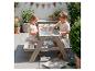Twee kinderen spelen met een houten picknicktafel met waterbak op een terras.