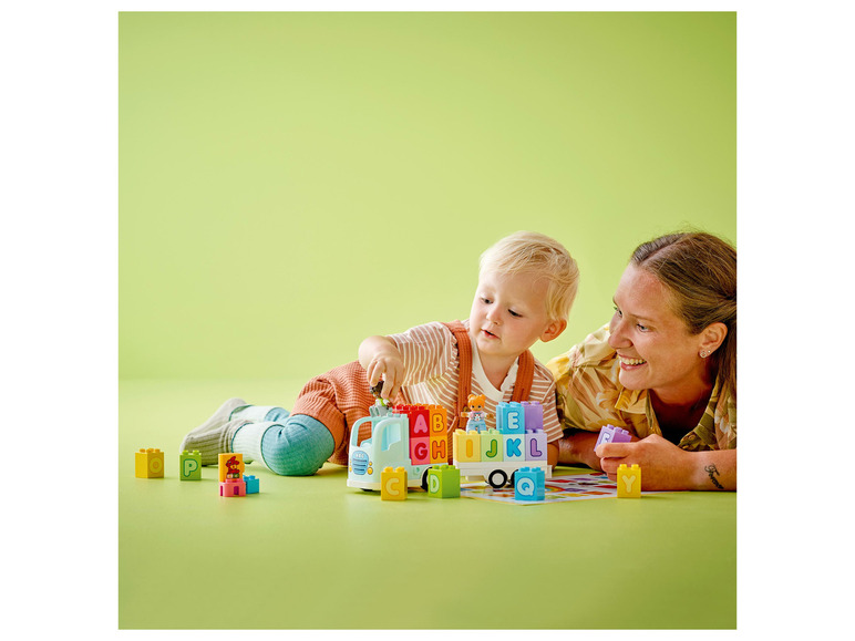 Een kind en een volwassene spelen met LEGO DUPLO blokken met letters.