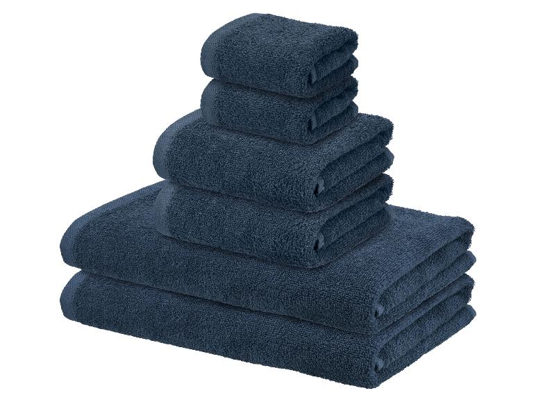 Stapel donkerblauwe handdoeken in verschillende maten op een witte achtergrond.