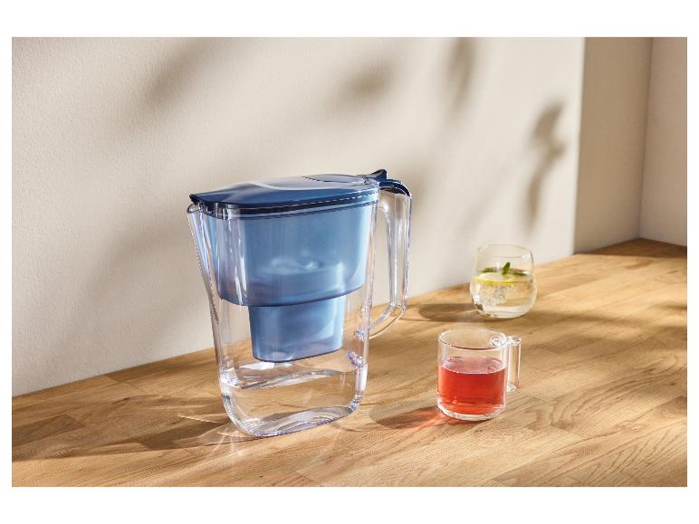 Waterfilterkan met twee glazen drankjes op een houten ondergrond.