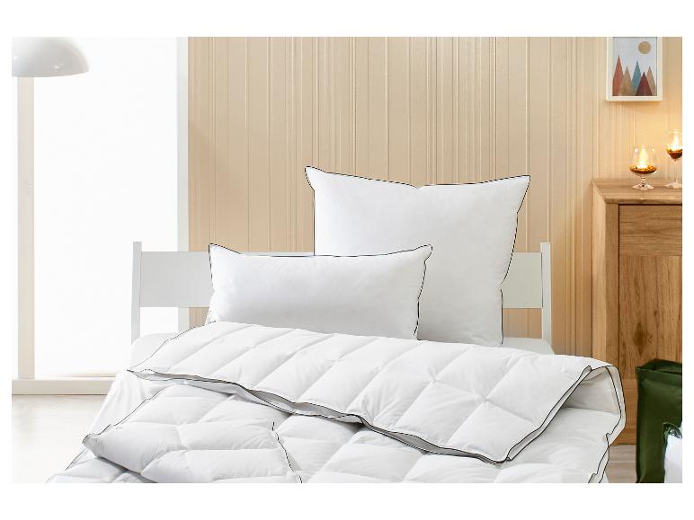 Wit dekbed en kussens met zwarte bies in een lichte slaapkamer.