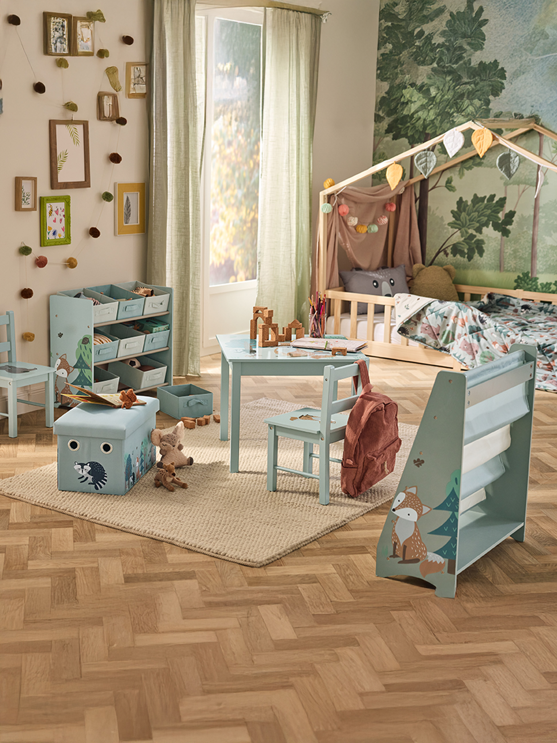 Een kinderkamer met bosthema, met een bed, tafel, stoelen en opbergmeubels.