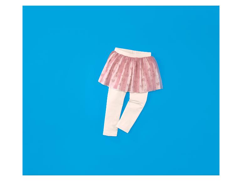 Roze tutu rokje voor peutermeisjes met regenboogprint over crèmekleurige legging op een blauwe achtergrond.