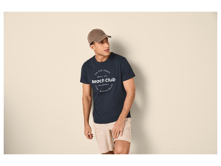 Man in een marineblauw T-shirt met 'Beach Club'-opdruk en gestreepte shorts