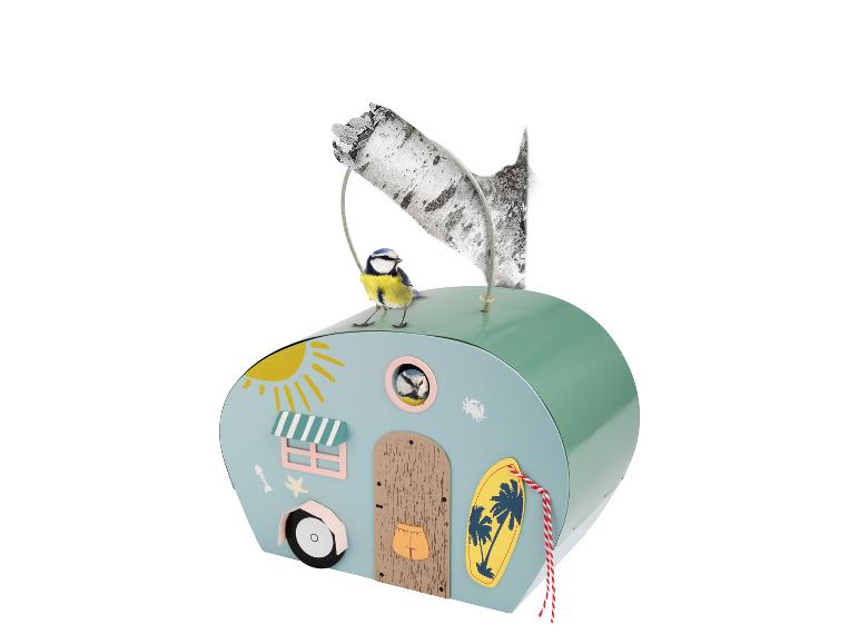 Caravanvormig vogelhuisje met een pimpelmees op het dak en één in het raam.