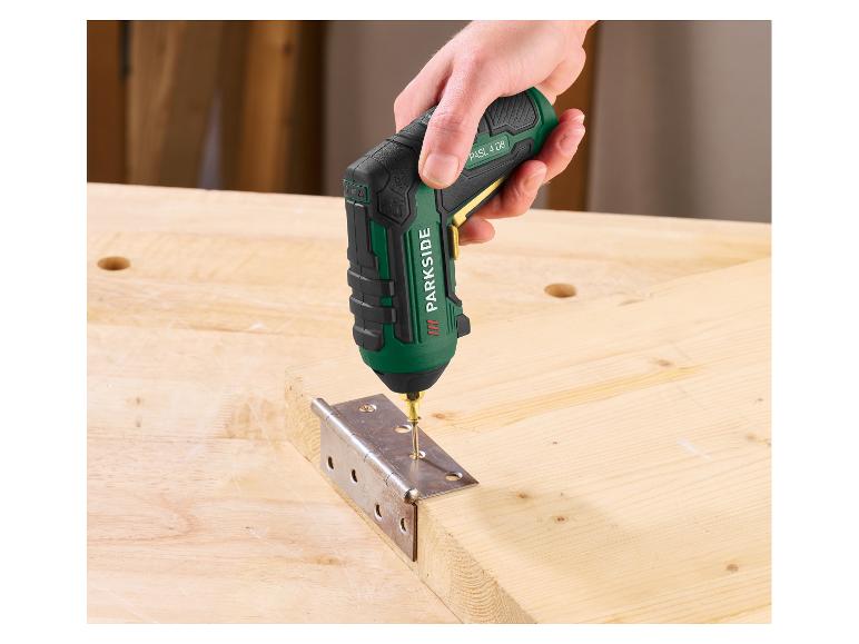 Een hand gebruikt een accuschroevendraaier om een scharnier op een houten plank te bevestigen.