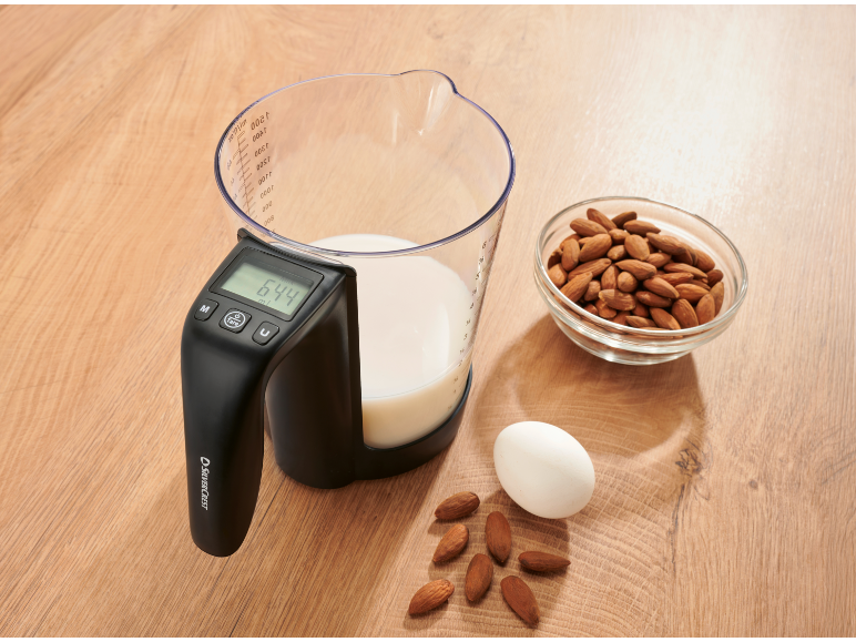 Maatbeker met digitale weegschaal die 644 ml aangeeft, naast amandelen en een ei.
