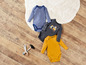 Drie baby onesies: een gestreepte, een met een graafmachine-print en een gele.