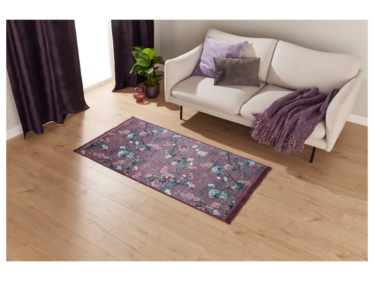 Een roze tapijt met bloemenmotief in een woonkamer met een bank