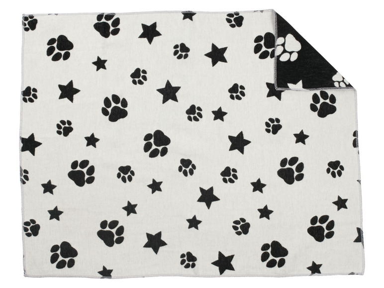 Een wit deken met zwarte hondenpootafdrukken en sterren.