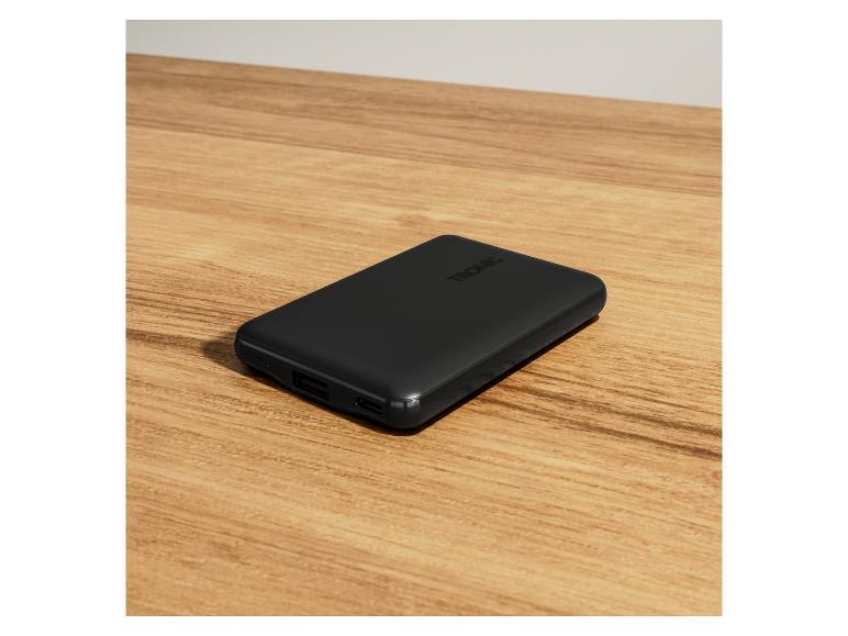 Een zwarte powerbank van het merk TRONIC op een houten tafel.