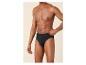 Man in zwarte slip, hand aan de tailleband, tegen een beige achtergrond.