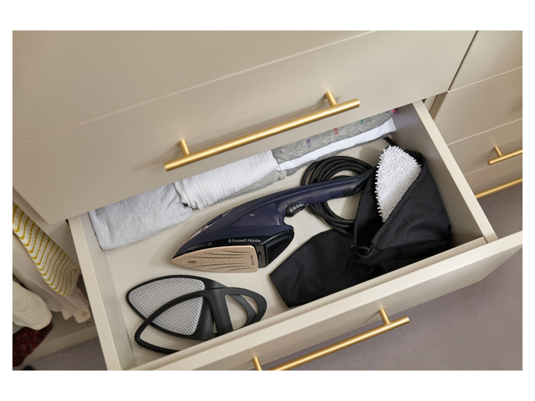 Een stoomstrijkijzer van Russell Hobbs in een lade met kleding en accessoires.