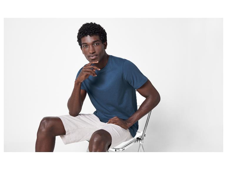 Een man in een blauwe T-shirt en witte korte broek.