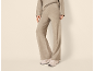 Vrouw in beige trainingspak met wijde broek en sportschoenen.